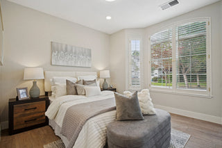 Bedroom_featuring_a_neutral_palette_white_bedding_dark_wood_nightstand