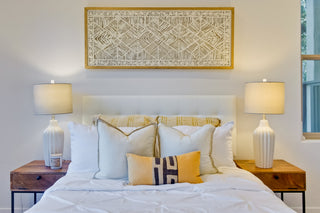 Bedroom with a neatly made bed, two lamps on nightstands, and a decorative wall art piece.
