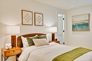 Neatly made bed with wooden headboard and nightstands in a bedroom setting.