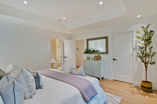 Bedroom with blue bedding, in the  wooden nightstands, and a window