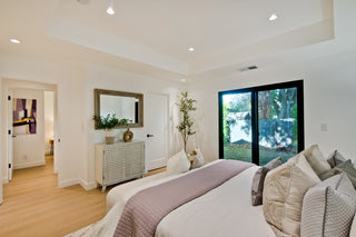Bedroom with blue bedding, in the  wooden nightstands, and a window