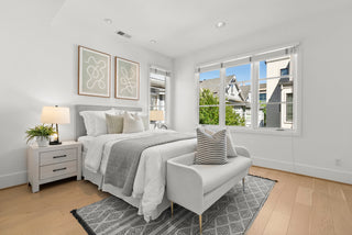 Modern bedroom with a bed, chair, and large window.
