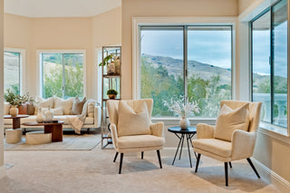 Modern living room with beige furniture and large windows overlooking a scenic view.