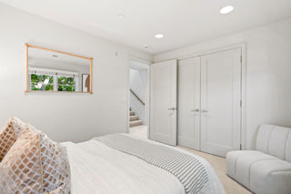 Modern bedroom with white walls, bed, and wardrobe.