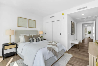 Modern bedroom with a bed, nightstands, and artwork on a white wall.