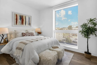 Modern bedroom with a bed, lamps, and a large window.