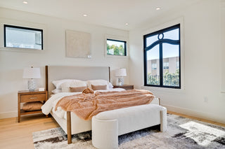 Modern bedroom with a bed, nightstands, and large windows.