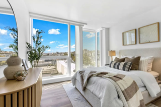 Modern bedroom with large windows, bed, and decorative elements.