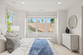 Modern bedroom with a bed, dresser, and large window