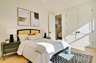Modern bedroom with bed, nightstands, and abstract art on the wall.