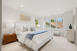 Modern bedroom with a large bed, nightstands, and a window view.