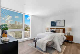 Modern bedroom with large windows, bed, and decor