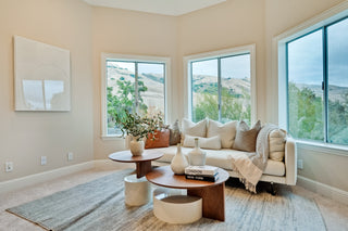 Modern living room with a sectional sofa, coffee table, and large windows.