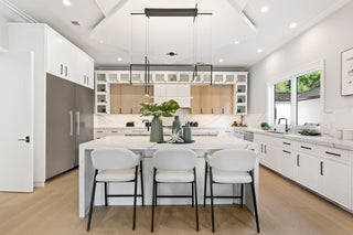 Modern kitchen with white cabinets, marble countertops, and stainless steel appliances.