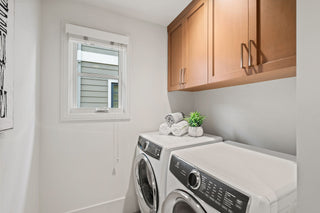 Laundry room with washer, dryer, and wooden cabinets.