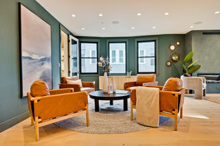 Modern living room with orange chairs, a round table, and decorative elements.