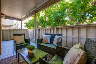 Outdoor patio with wicker furniture, table, and greenery