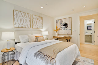 Neatly made bed in a bedroom with decorative elements and a lamp.