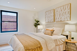 Modern bedroom with a bed, lamps, and abstract wall art.