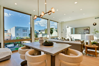 Modern living room with a dining table and chairs, large windows, and a view of a cityscape.