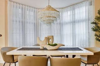 Dining room with a table, chairs, and a chandelier in front of large windows.
