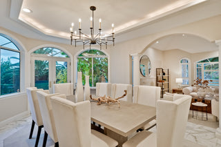 Elegant dining room with a chandelier, table, and chairs in a well-lit room.