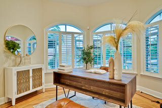 Modern home office with wooden desk, white cabinet, and large windows.