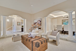 Modern living room with a wooden coffee table, white chairs, and decorative elements.