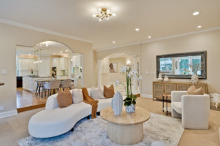 Modern living room with white furniture, wooden coffee table, and decorative elements.
