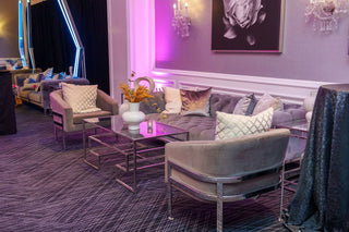Luxurious living room with purple and gray decor, featuring a sofa, chairs, and decorative elements.
