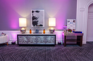 Decorative room with a console table, lamps, and framed picture on a purple wall.