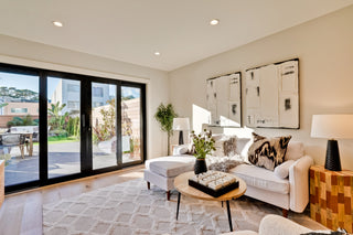 Modern living room with large sliding glass doors, white sofa, and decorative elements.