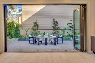 Open sliding glass door revealing a patio with outdoor furniture and plants.
