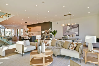 Modern living room with white furniture, neutral decor, and large windows.