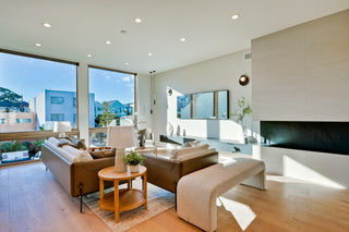Modern living room with large windows, beige sofa, and wooden coffee table.