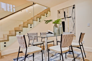 Dining area with glass table and chairs near a staircase