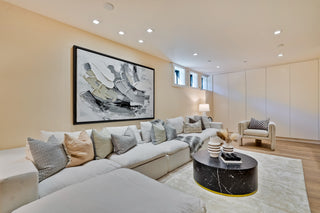 Modern living room with a large sectional sofa, coffee table, and abstract art on the wall.