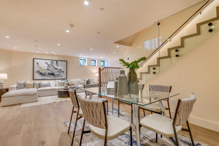 Modern living room with glass dining table and staircase in the background