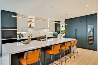 Modern kitchen with white countertops, blue cabinets, and orange bar stools.