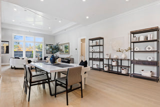Modern dining room with a long table and chairs, large windows, and decorative elements.