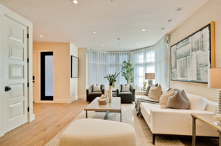 Modern living room with beige sofa, ottoman, and decorative items.