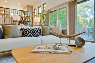 Living room with a white sofa, decorative pillows, and a wooden coffee table with a book and decorative items.
