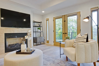 Living room with beige sofa, ottoman, and fireplace.