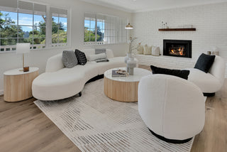 Modern living room with white sectional sofa, round coffee table, and fireplace.