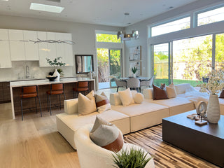 Sweet living room with white walls, large windows, and a white sofa.