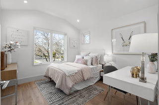 Modern bedroom with a bed, desk, and large window.