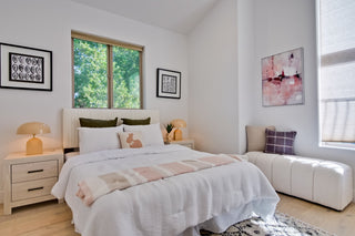 Modern bedroom with a bed, nightstands, and artwork on a white wall.