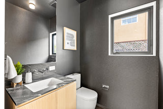 Modern bathroom with gray walls, a sink, and a toilet.