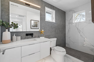 Modern bathroom with gray tiled walls, white fixtures, and a starfish decoration.