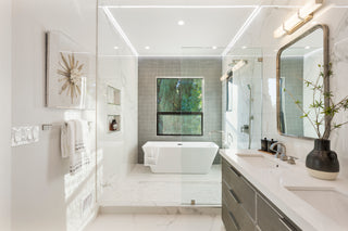 Modern bathroom with white tiles, a freestanding bathtub, and a vanity area.